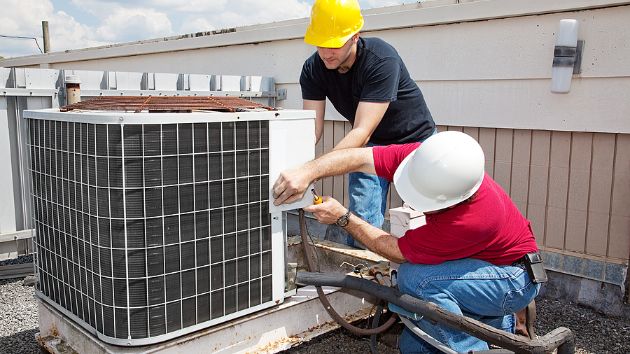 Two HVAC workers replacing a home AC unit.