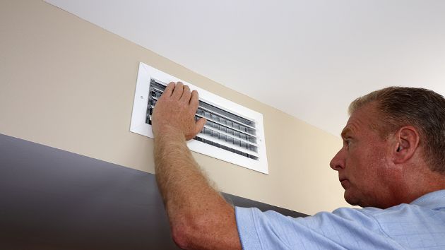 Someone checking an air conditioning vent.