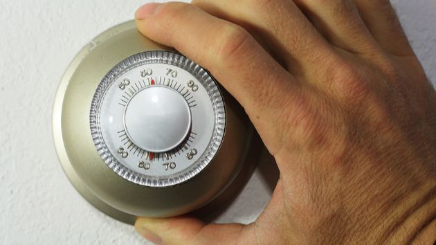 person adjusting the settings on a thermostat