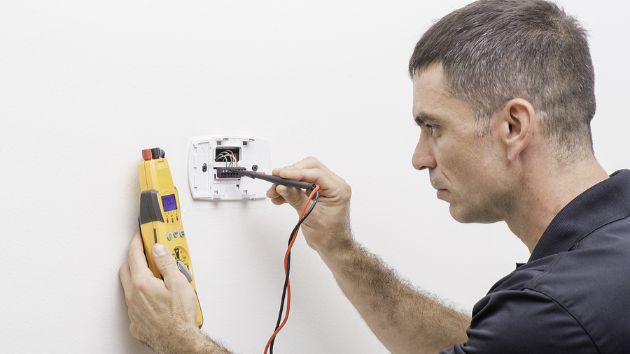 Decoding AC Error Codes: When Is It A Real Emergency? Technician working on a thermostat unit.
