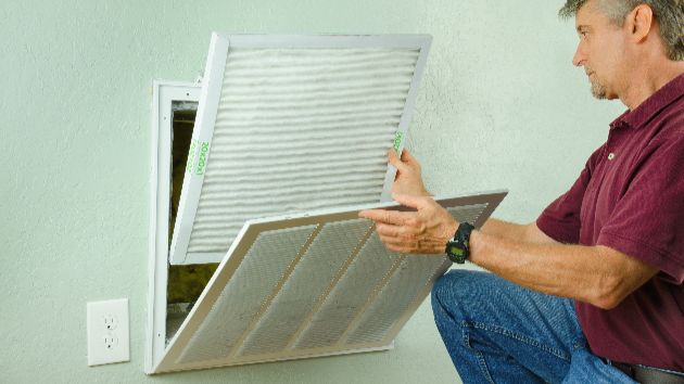 AC technician changing the AC filter from an air vent.