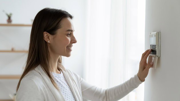 Person inside their home adjusting their thermostat.
