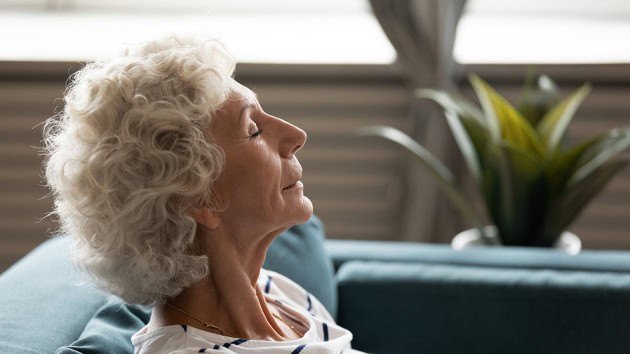 Person sitting on couch inside their home, enjoying the refreshing sensation of clean, high-quality air.
