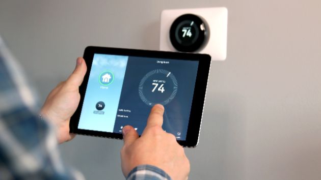 A technician adjusting the thermostat after a new AC install.