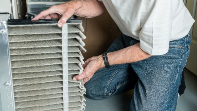 A technician working on an HVAC system, which has been damaged by heat.