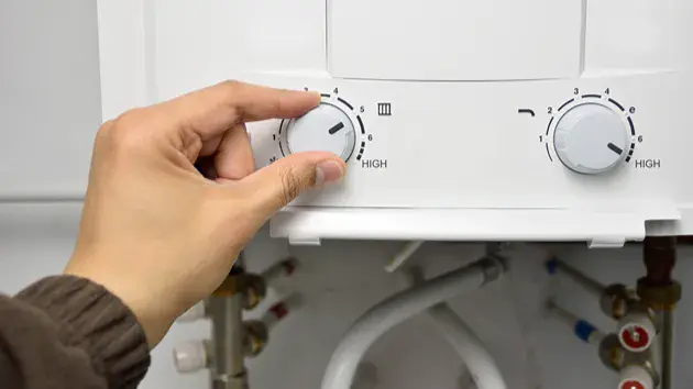 What Causes An Electric Furnace To Blow Cold Air? Person changing the settings on an electric furnace.